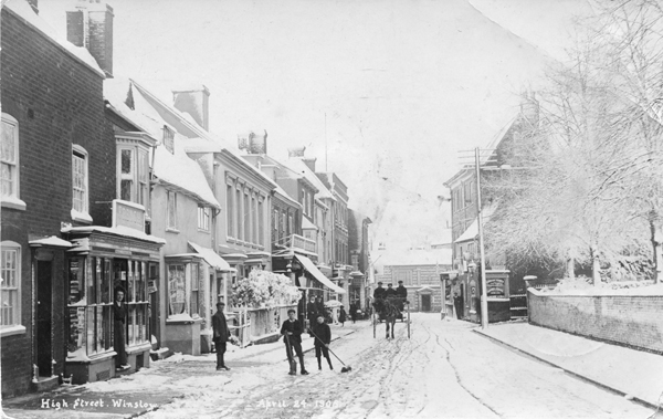 High Street covered with snow, woman standing in shop doorway